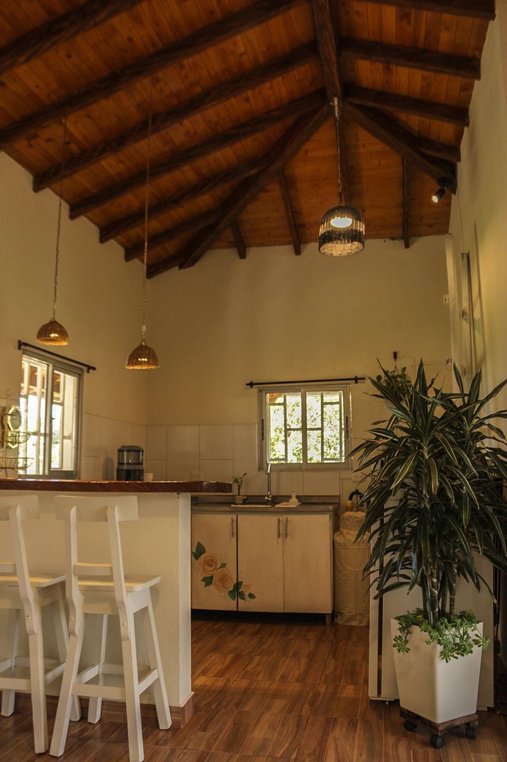 Cocina de Casa Taná con barra, lámparas de fibra y techo de madera a dos aguas